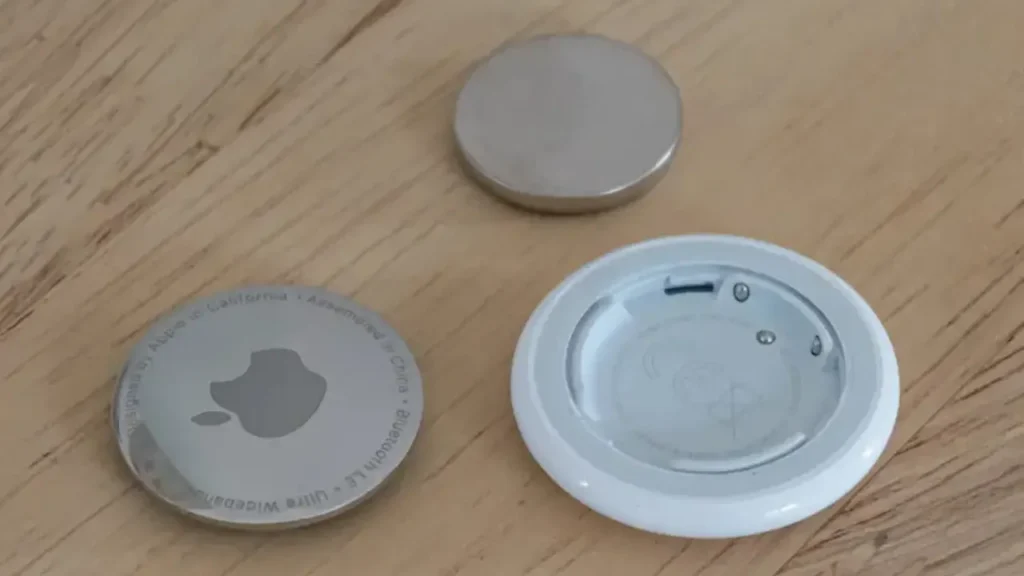 An Open AirTag Along with An Old and A New Batter on A Wooden Surface - How To Change AirTag Battery?